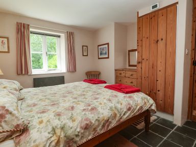 A bedroom with a bed and dresser at Swallows, St Keverne, Lizard Peninsula
