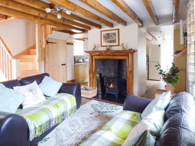 A living room with two leather sofas and a fireplace at Fell View Cottage in Bootle near Millom