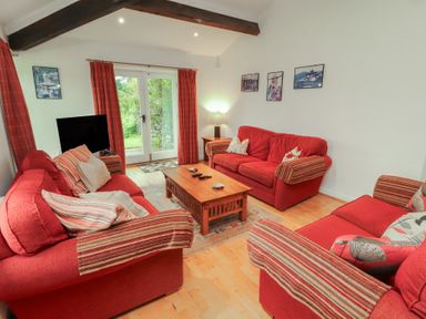 A living room with red sofas and a coffee table at Winster Fields in Cartmel Fell near Windermere