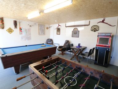 A game room with a foosball table pool table arcade machine and seating at Garth Morthin The Barn in Porthmadog