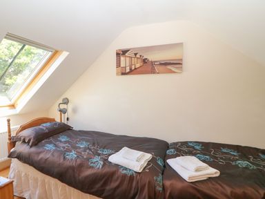 A bedroom with two single beds under a slanted ceiling with a skylight window at Garth Morthin The Stables in Porthmadog