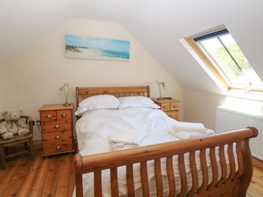 A bedroom with a wooden bed and bedside tables under a skylight window at Garth Morthin The Stables in Porthmadog