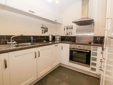 A kitchen with white cabinets stainless steel oven and sink at Garth Morthin The Stables in Porthmadog