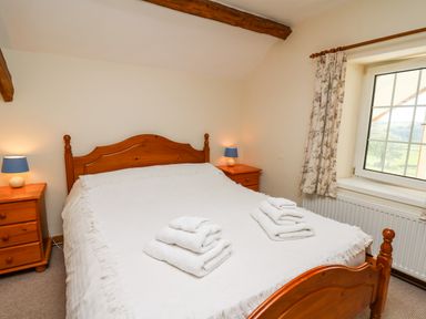 A bedroom with a wooden bed and two bedside tables with lamps at Llety'r Wennol in Ffarmers near Lampeter