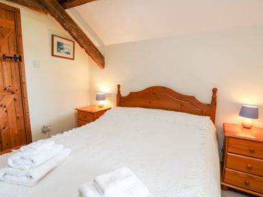 A bedroom with a double wooden bed white bedding bedside tables and lamps at Llety'r Wennol Ffarmers near Lampeter