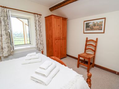A bedroom with a wooden wardrobe a wooden chair and a bed with towels on it at Llety'r Wennol in Ffarmers near Lampeter