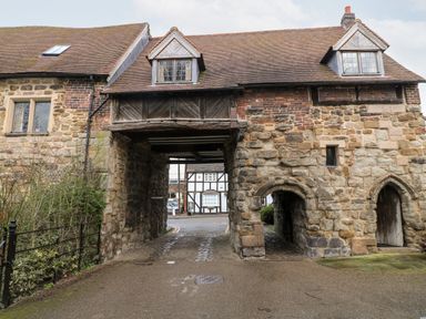 An old stone archway building with a passage and windows at Porters Lodge in Polesworth