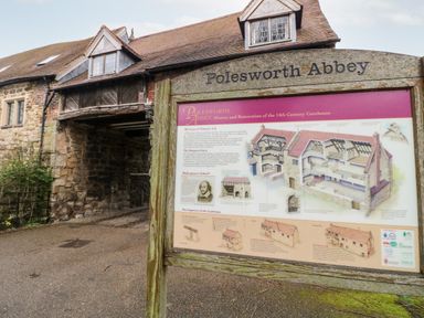 An information board about Polesworth Abbey in front of a stone and brick building with an archway at Polesworth Abbey in Polesworth