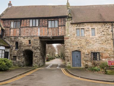 An old stone and brick building with an archway and a road passing underneath at Porters Lodge in Polesworth