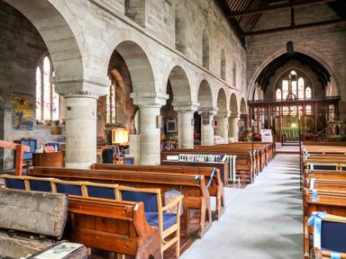 The interior of a church with wooden pews stone arches stained glass windows and an altar at Porter's Lodge in Polesworth