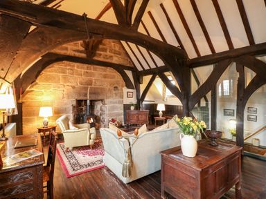 A living room with wooden beams stone fireplace sofa armchair and wooden furniture at Porters Lodge in Polesworth