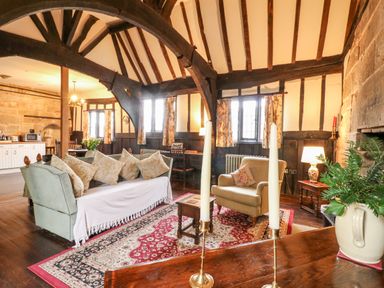 A living room with wooden beams and a stone fireplace at Porter's Lodge in Polesworth