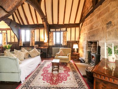 A living room with a sofa armchair coffee table wood burning stove and wooden beams at Porter's Lodge in Polesworth