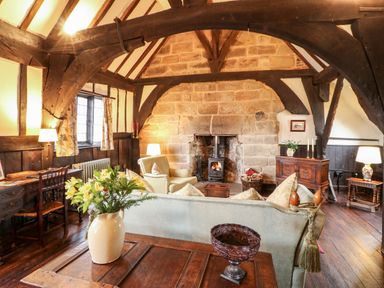 A living room with wooden beams stone fireplace and wooden furniture at Porter's Lodge in Polesworth