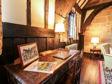 A wooden desk with a framed picture a lamp and magazines in a room with wooden beams at Porters Lodge in Polesworth