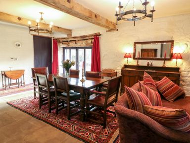 A dining room with wooden table and chairs a sideboard and a sofa with striped cushions at Gatehouse Croft in Polesworth