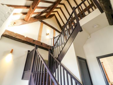 A staircase with dark wooden rails and exposed ceiling beams in a hallway at Gatehouse Croft in Polesworth