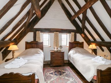 A bedroom with two single beds a wooden dresser between them and exposed wooden beams on the ceiling at Gatehouse Croft in Polesworth