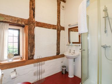 A bathroom with a pedestal sink shower cubicle and window with curtains at Gatehouse Croft in Polesworth