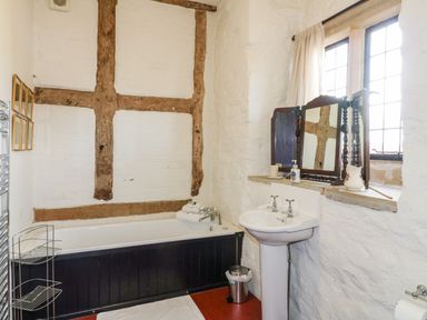 A bathroom with a bathtub sink mirror and window at Gatehouse Croft in Polesworth