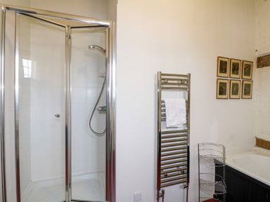 A bathroom with a glass shower enclosure a heated towel rail towel rack and framed pictures on the wall at Gatehouse Croft Polesworth