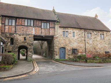 An old stone and brick building with archways and wooden windows at Gatehouse Croft in Polesworth