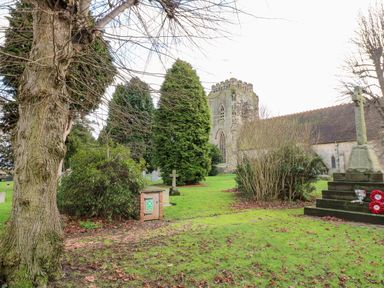 A churchyard with tombstones trees and a war memorial at Gatehouse Croft in Polesworth