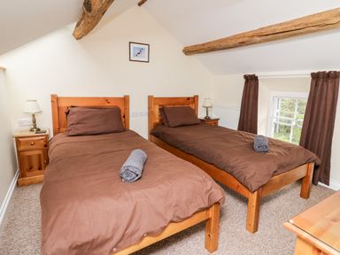 A bedroom with two single wooden beds with brown bedding and rolled towels on them at Penlon in Capel Bangor near Aberystwyth