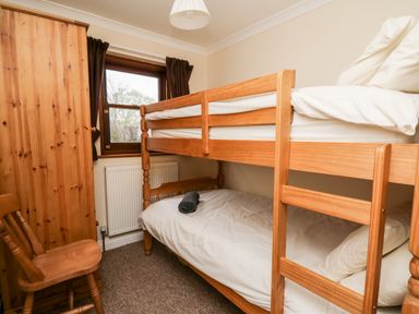 A bedroom with bunk beds a wooden chair and a wardrobe at Penlon in Capel Bangor near Aberystwyth
