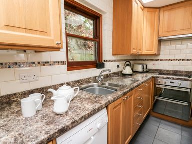 A kitchen with wooden cabinets white teapot kettle toaster and sink at Penlon in Capel Bangor near Aberystwyth