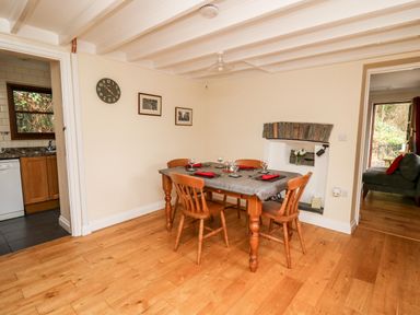 A dining room with a table set for four near a small brick fireplace at Penlon in Capel Bangor near Aberystwyth