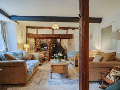 A living room with sofas, a coffee table, and a fireplace at Church Farmhouse in Winsham