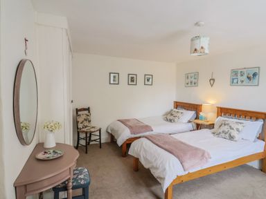 A bedroom with two beds and a chair at Church Farmhouse in Winsham