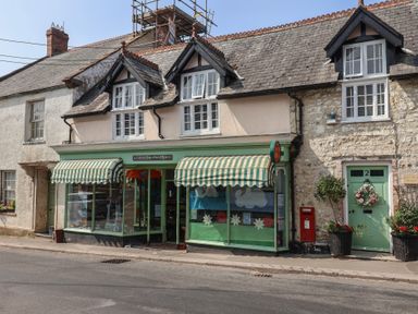 A post office store with green and white awnings in Winsham