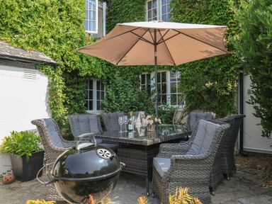 A garden with a dining table and chairs at Church Farmhouse in Winsham