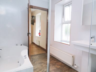 A bathroom with a bathtub a sink a radiator and a window at Fernleigh Cottage in Allithwaite near Grange-over-Sands