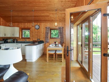 Kitchen and dining area with wooden walls and ceiling at Barn Shelley Lodge in Copplestone near Crediton