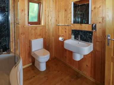 A bathroom with a toilet sink bathtub and a window at Barn Shelley Lodge in Copplestone near Crediton