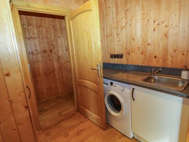 A laundry room with a washing machine sink and wooden walls at Barn Shelley Lodge Copplestone near Crediton