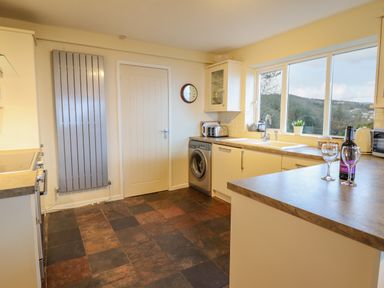 A kitchen with tiled floor sink washing machine toaster and window with outdoor view at The Villa in Harlech