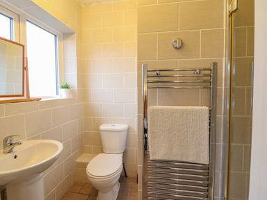 A bathroom with a sink toilet towel rack and a window at The Villa in Harlech