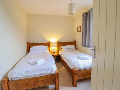 A bedroom with two single beds wooden frames and white bedding at The Villa in Harlech
