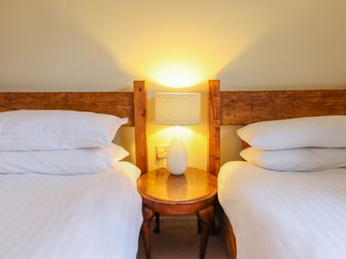 A bedroom with two single beds separated by a wooden table with a lamp at The Villa in Harlech