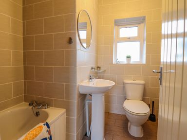 A bathroom with a bathtub sink toilet mirror and small window with a plant at The Villa in Harlech