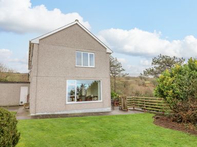 Exterior view of a two-story house with a grass lawn and wooden fence at The Villa in Harlech