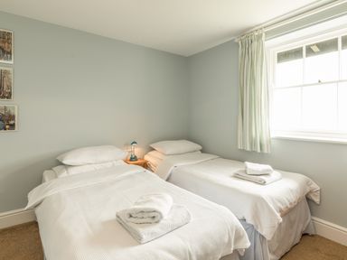 A bedroom with two single beds two bedside tables and a window at 3B Coastguard Cottages in Low Newton-By-The-Sea