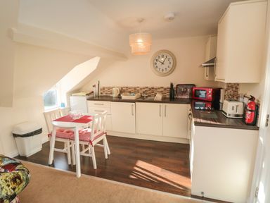 A kitchen with white cabinets a table with two chairs and kitchen appliances at Carisbrooke House Apartment 6 in Scarborough
