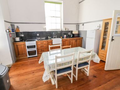 A kitchen with wooden cabinets a dining table with chairs and a glass display cabinet at The Old School House in Gortermone near Carrigallen County Leitrim