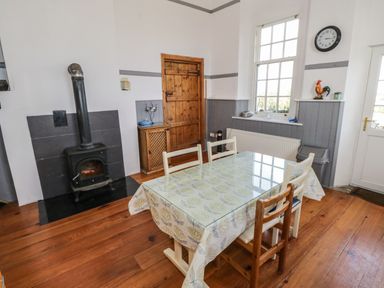 A dining area with a wood stove a wooden door and a table with chairs near a window at The Old School House in Gortermone near Carrigallen County Leitrim