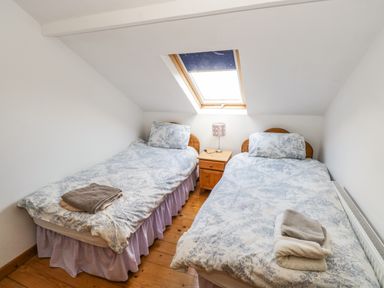 A bedroom with two single beds a wooden nightstand lamp and a skylight window at The Old School House in Gortermone near Carrigallen County Leitrim